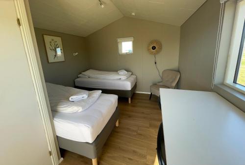 a small room with two beds and a chair at Smabot - riverside cottage in Egilsstaðir