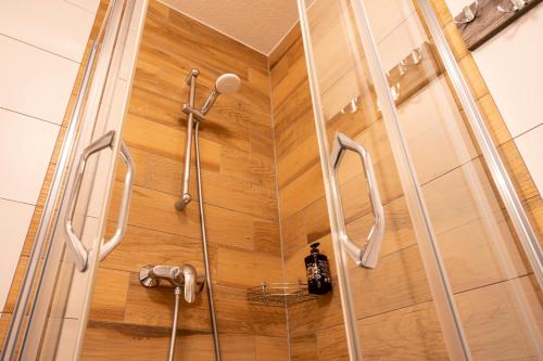 a shower in a bathroom with a wooden wall at Apartmánový dom Štiavnica in Liptovský Ján