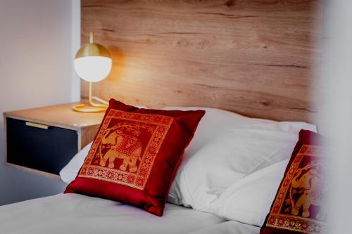 a bed with two red pillows on top of it at Apartamenty Cicha - bezpłatny parking in Krynica Zdrój