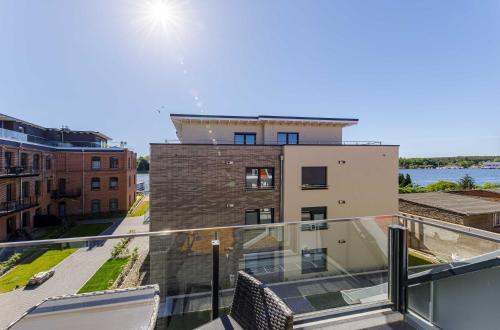 a glass balcony with a view of a building at SeeGlück Malchow - Stilvolle Maisonette mit Balkonen & Seeblick in Malchow