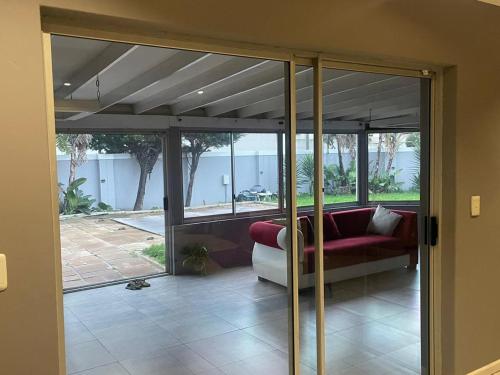 een woonkamer met glazen deuren en een rode bank bij Zoe & Saint in Kaapstad