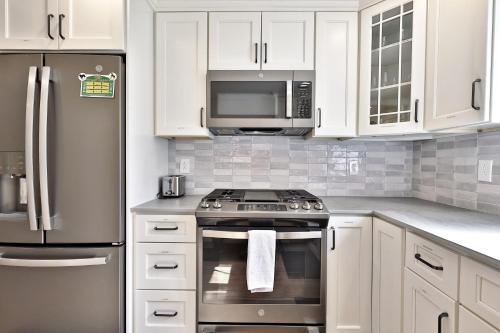 una cucina con armadietti bianchi, piano cottura e forno a microonde di The Family Retreat at Bomoseen home a Castleton