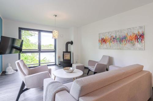 a living room with a couch and chairs and a table at Shanti-Suite mit Dachterrasse, Kamin & Sauna am Krakower See in Krakow am See