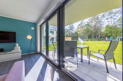 a living room with sliding glass doors and a table and chairs at Bewusstsein - Modernes Apartment mit Terrasse, Walk-In-Dusche & Wellnesszugang in Krakow am See
