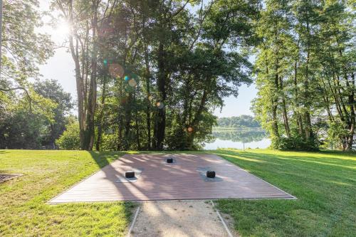 a picnic table in the middle of a field with a lake at Bewusstsein - Modernes Apartment mit Terrasse, Walk-In-Dusche & Wellnesszugang in Krakow am See