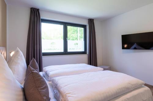 a bedroom with two beds and a window at Glücksraum - Modernes Apartment mit Panoramablick, Kamin & Wohlfühlambiente in Krakow am See