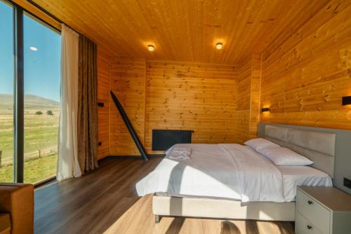 Cottage Tabatskuri في Molit'i: غرفة نوم بجدران خشبية وسرير مع موقد