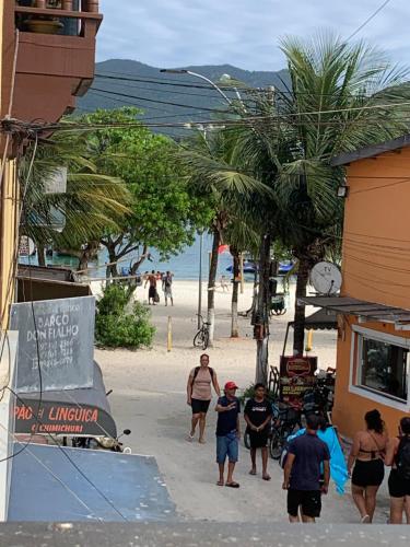 a group of people walking down a sidewalk on a beach at Flet pé na areia dos anjos in Arraial do Cabo