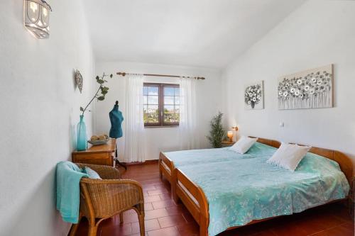 a bedroom with a bed and a chair and a window at Benagil sea-view apartment Neptuno 4 in Benagil