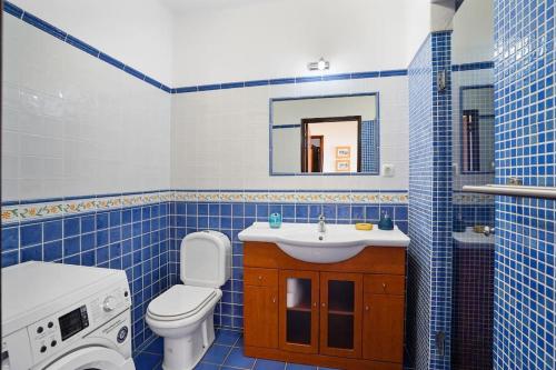 a blue tiled bathroom with a toilet and a sink at Benagil sea-view apartment Neptuno 4 in Benagil