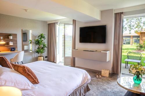 a bedroom with a bed and a tv on a wall at Domaine la Charpinière, The Originals Collection in Saint-Galmier