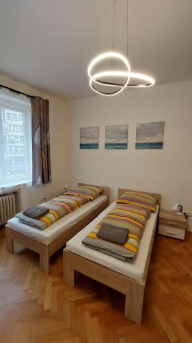 two beds in a room with a chandelier at Bonvolon in Prague
