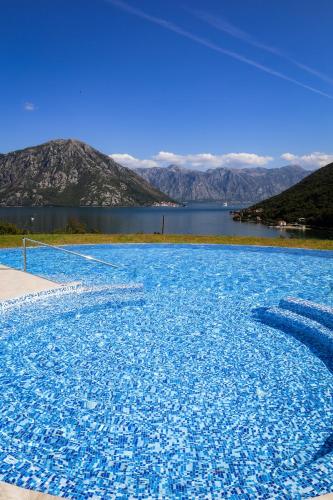 a large blue swimming pool with a view of a lake at Morinj Lavender Bay apartment E5 in Donji Morinj