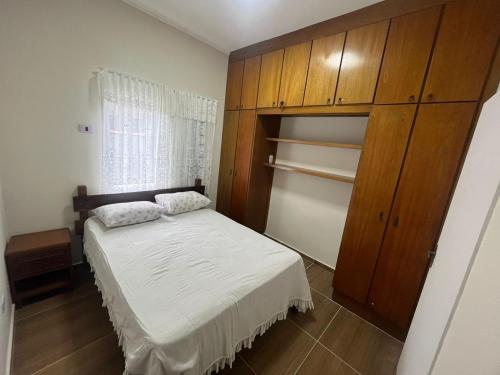 une chambre avec un lit et une armoire en bois dans l'établissement Casa Centro de Bertioga - SP terrea 300 metros da praia - Marcondes 05, à Bertioga