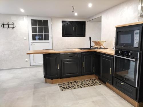 La cuisine est équipée de placards noirs, d'un évier et d'un four micro-ondes. dans l'établissement Le Gite du Planey, à Plainemont