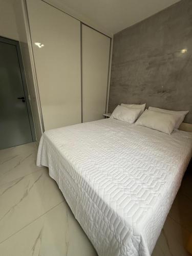 a bedroom with a large bed with white sheets at Apartamento no centro de Jardim Camburi in Vitória