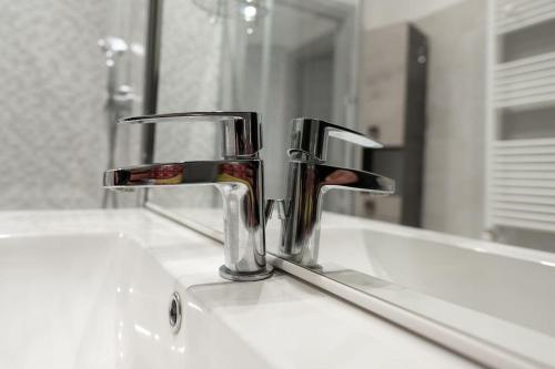 a bathroom sink with a faucet and a mirror at Appartamento Lussuoso in Lodi