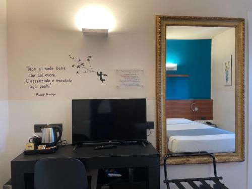 a mirror in a room with a bed and a television at Hotel Europa Varese in Varese
