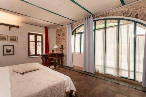 a bedroom with a bed and a large window at Le Suite di Borgo Casa Scaparone in Biglini