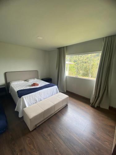 a bedroom with a bed and a large window at Casas Regiao de Pedra Azul Cverde in Domingos Martins