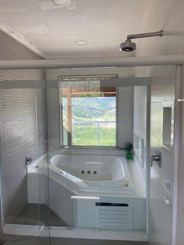 a white bathroom with a tub and a window at Casas Regiao de Pedra Azul Cverde in Domingos Martins