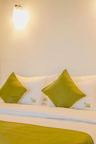a bed with green and white pillows on it at Lindy Stays Talpe in Pitiduwa