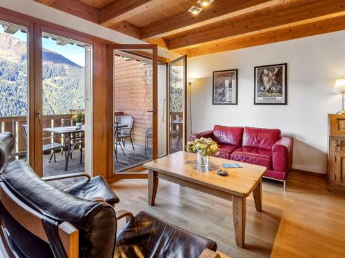 a living room with a red couch and a table at Apartment Racer's Retreat Apt-07 by Interhome in Wengen