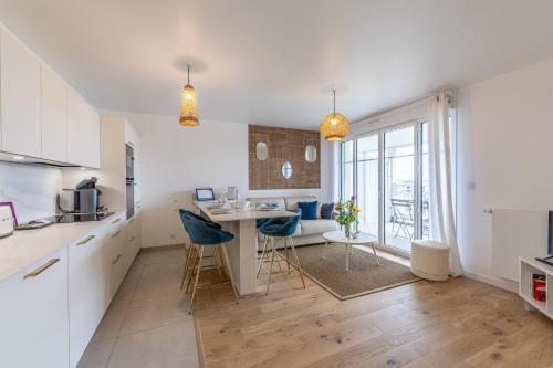 une cuisine avec des armoires blanches et une table avec des chaises dans l'établissement Ty Enogat- Proche de la plage, garage privé, à Dinard