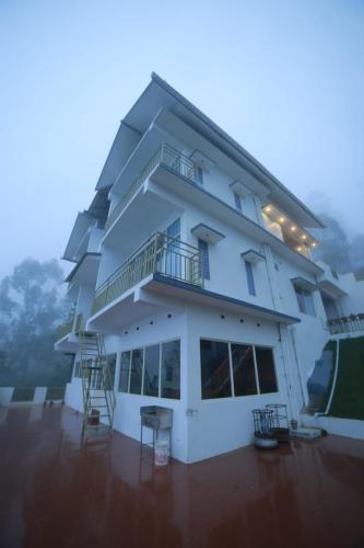 a large white building with a balcony and chairs at Sky Elanza in Munnar