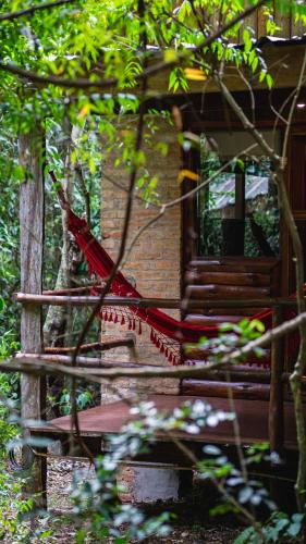 a red hammock in front of a house at La Aldea De La Selva Lodge in Puerto Iguazú