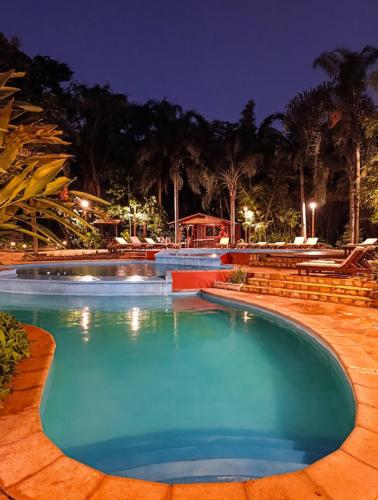 a large swimming pool at a resort at night at La Aldea De La Selva Lodge in Puerto Iguazú