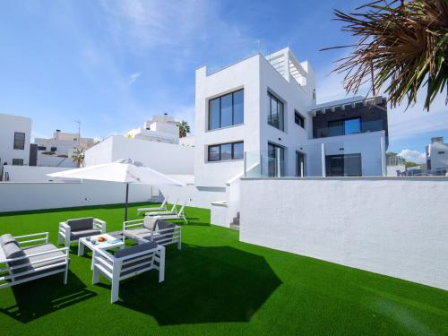 une maison blanche avec des chaises et un parasol dans l'établissement Villa Villa Dorada by Interhome, à La Cala de Finestra