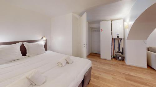 - une chambre avec un grand lit blanc et des oreillers blancs dans l'établissement Studio Castelnau, à Strasbourg