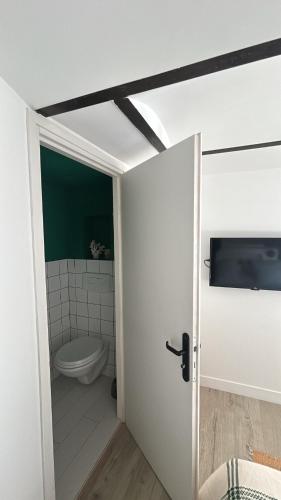 La salle de bains est pourvue de toilettes blanches et d'une porte. dans l'établissement Place aux huiles, à Marseille