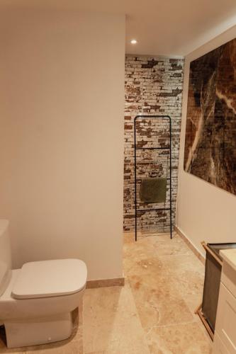 La salle de bains est pourvue de toilettes et d'un mur en briques. dans l'établissement L'Olivier, à Mormoiron