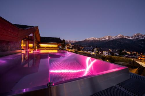 a swimming pool with pink lights on top of a house at Hotel Tirol Fiss 4Sterne Superior in Fiss