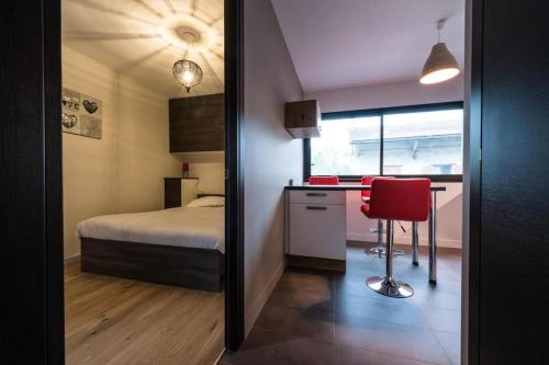une chambre avec un lit et un bureau avec une chaise rouge dans l'établissement La Clé des Champs, à Annecy