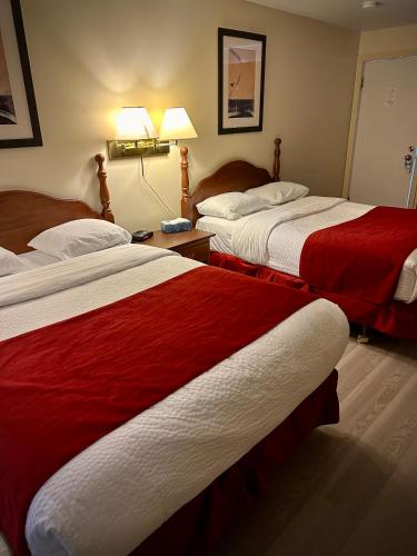 a hotel room with two beds with red sheets at Ceilidh Country Lodge in Baddeck
