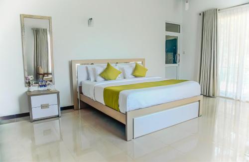 a white bedroom with a large bed with yellow pillows at Lindy Stays Talpe in Pitiduwa