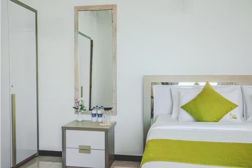 a bedroom with a green and white bed and a table at Lindy Stays Talpe in Pitiduwa
