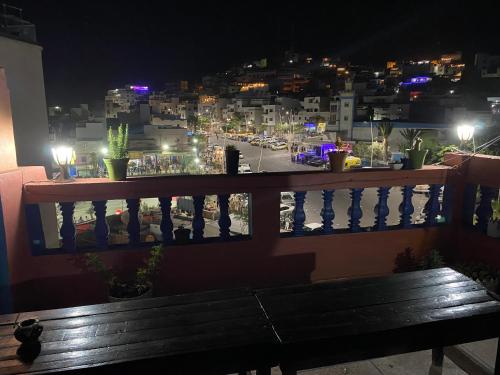 a bench on a balcony with a view of a city at night at Taliouine Apartments in Taghazout