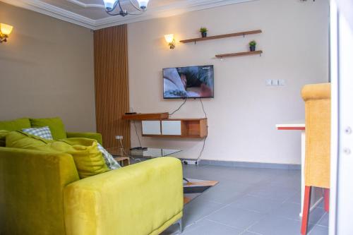 a living room with a yellow couch and a tv at New 237 de Luxe in Yaoundé