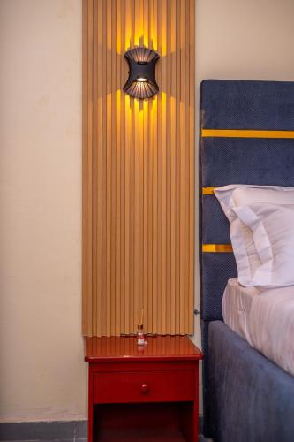 a bedroom with a bed and a table with a lamp at New 237 de Luxe in Yaoundé