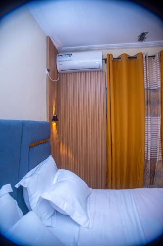 a bedroom with a bed and a yellow curtain at New 237 de Luxe in Yaoundé