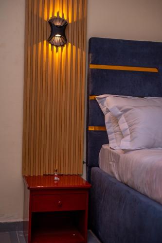 a bedroom with a bed and a table with a lamp at New 237 de Luxe in Yaoundé