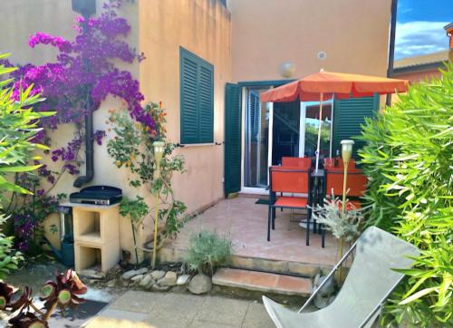 un patio avec une table et un parasol dans l'établissement Immo A2L Lozari, à Belgodère