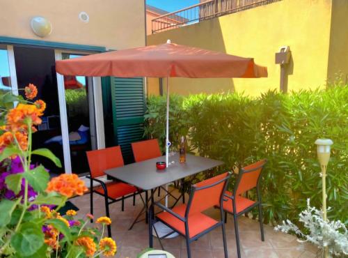 une table avec des chaises et un parasol sur une terrasse dans l'établissement Immo A2L Lozari, à Belgodère