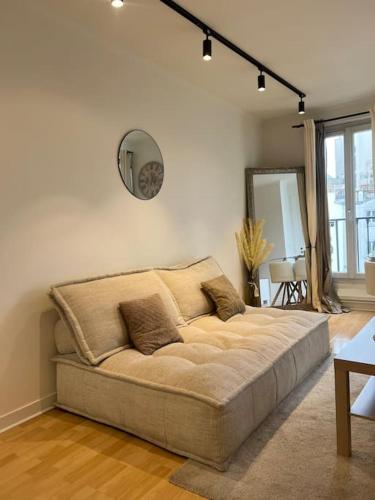 - un grand canapé dans le salon avec un miroir dans l'établissement Appartement Paris vue Tour Eiffel Trocadéro, à Paris