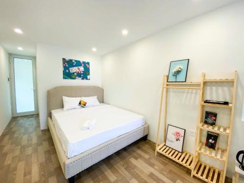 a bedroom with a bed with white sheets and wooden floors at Eco Nest Apartment & Hotel Nam Ngư in Hanoi
