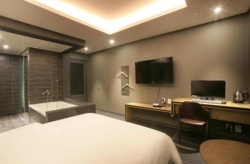 a hotel room with a bed and a tub and a television at Zenith Hotel Bupyeong in Incheon